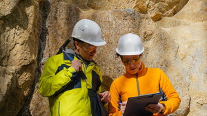 Two geologists looking at a clipboard in the field.