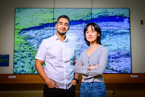 Mark Lara and Zhuoxuan Xia standing in front of a digital display.