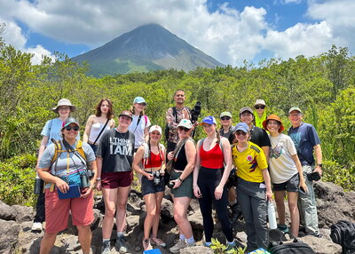 A group photo with a jungle and mountain behind them.