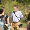 A man standing front of a crowd of out of focus students pointing.