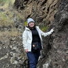 A person standing next to a rocky cliff dressed in winter clothing.