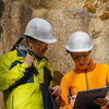 Two geologists looking at a clipboard in the field.