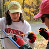 Two students taking a tree ring core from a tree.