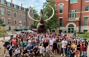 group of people waving in front of a mammoth statue