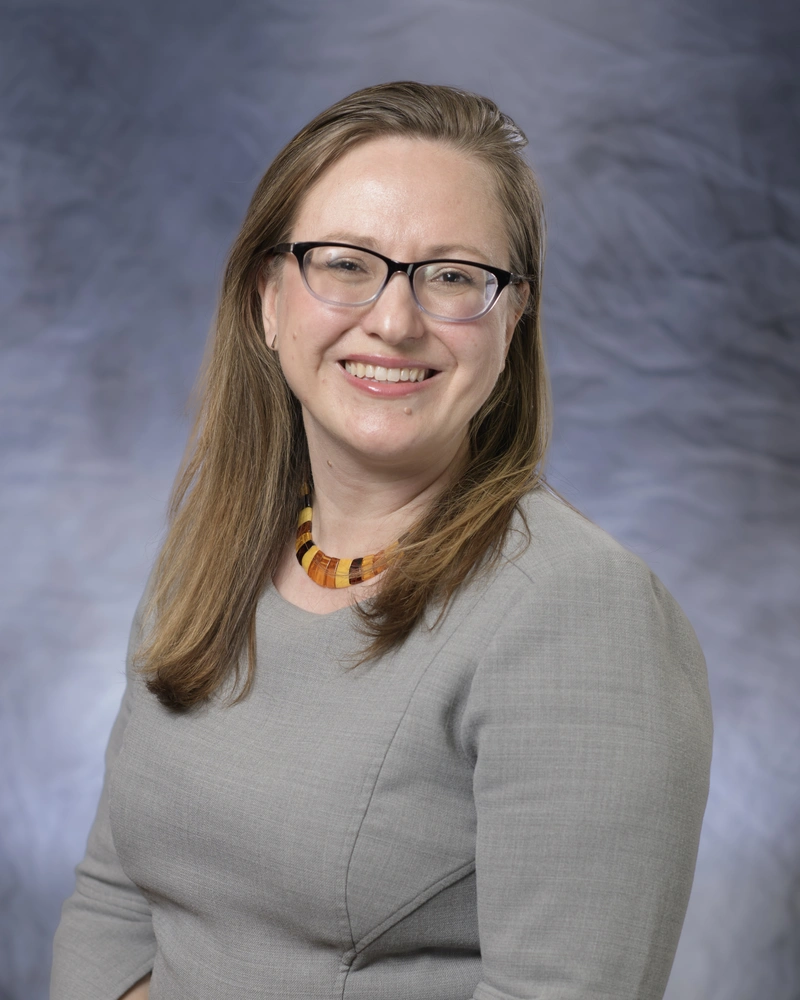 A woman with glasses posing for a headshot.