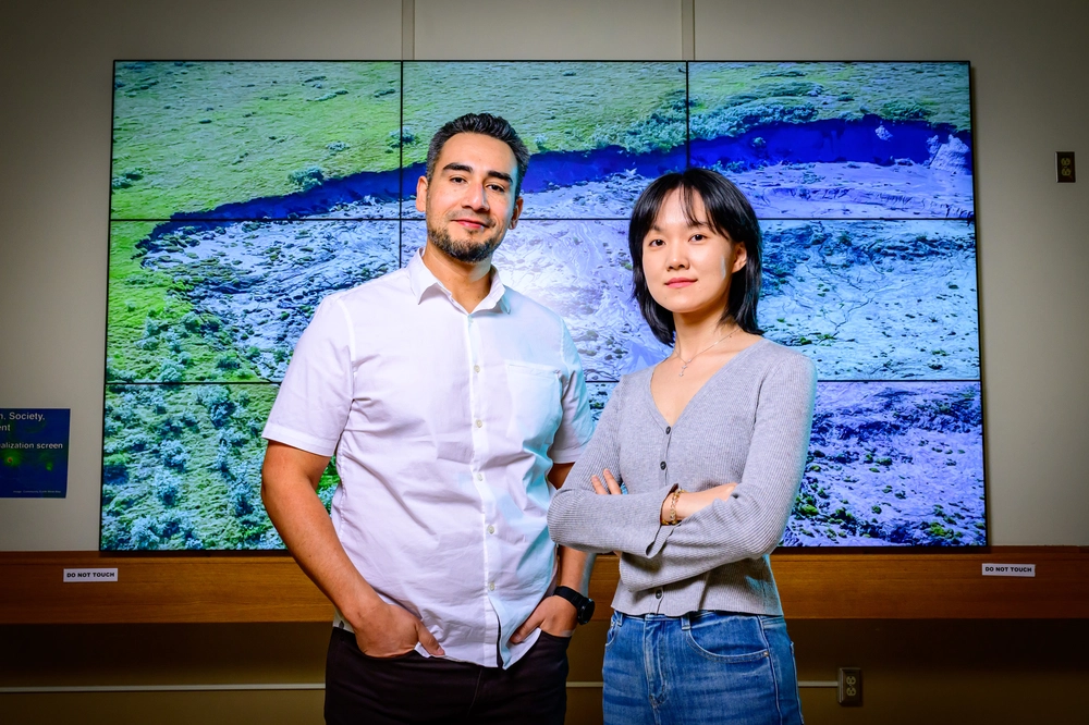 Mark Lara and Zhuoxuan Xia standing in front of a digital display.
