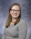 A woman with glasses posing for a headshot.